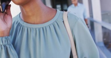 Ofiste akıllı telefon kullanan Afro-Amerikan iş kadınının videosu. İş adamları ve ofis kavramında çalışmak.