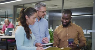 Çeşitli erkek ve kadın iş arkadaşları konuşuyor ve ellerinde belgeler var. Modern bir ofiste çalışmak..
