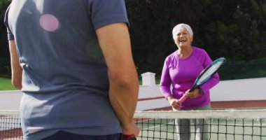 Çift ırklı mutlu çiftin tenis kortundan sonra el çırpışlarının videosu. aktif emeklilik yaşam tarzı, kıdemli ilişki ve tenis eğitim konsepti.
