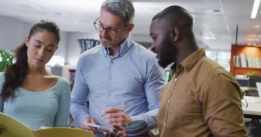 Çeşitli erkek ve kadın iş arkadaşları konuşuyor ve ellerinde belgeler var. Modern bir ofiste çalışmak..