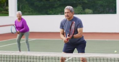 Tenis kortunda antrenman yaparken çift ırklı mutlu çiftin videosu. aktif emeklilik yaşam tarzı, kıdemli ilişki ve tenis eğitim konsepti.