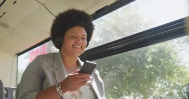 Otobüste akıllı telefon kullanan mutlu ve melez bir kadın. dijital göçebe hareket halinde, beden içeriği.