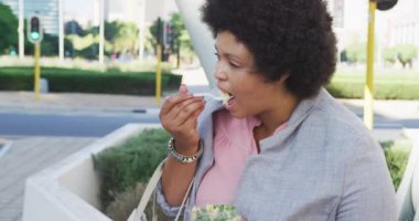 Ayrıca şehirde salata yiyen melez bir kadın. dijital göçebe hareket halinde, beden içeriği.