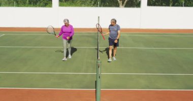 Tenis kortunda maçtan sonra yürüyen mutlu son sınıf çifti videosu. aktif emeklilik yaşam tarzı, kıdemli ilişki ve tenis eğitim konsepti.