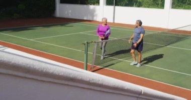 Çift ırklı mutlu çiftin tenis kortunda el çırpışlarının videosu. aktif emeklilik yaşam tarzı, kıdemli ilişki ve tenis eğitim konsepti.