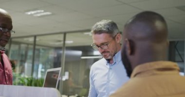 Çeşitli erkek iş arkadaşları konuşuyor ve dizüstü bilgisayar kullanıyor. Modern bir ofiste çalışmak..