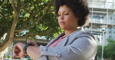 Artı, çift ırklı bir kadın akıllı olanı kontrol ediyor ve şehirde yürüyor. dijital göçebe hareket halinde, beden içeriği.