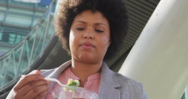 Ayrıca şehirde salata yiyen melez bir kadın. dijital göçebe hareket halinde, beden içeriği.