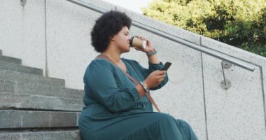 Mutlu ve melez bir kadın akıllı telefon kullanıyor ve kahve içiyor. dijital göçebe hareket halinde, beden içeriği.