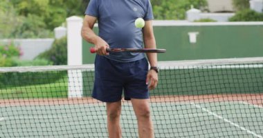 Elinde raket tutan ve tenis kortunda top atan mutlu son sınıf öğrencisinin videosu. aktif emeklilik yaşam tarzı, hobi ve tenis eğitim konsepti.