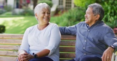 Çifte kıdemli çiftin bahçede bankta oturup kucaklaşmalarını gösteren bir video. aktif emeklilik yaşam tarzı, kıdemli ilişki ve birlikte zaman geçirme kavramı.