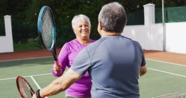 Tenis kortundaki maçtan sonra çiftler arası mutlu çiftin kucaklaşmasının videosu. aktif emeklilik yaşam tarzı, kıdemli ilişki ve tenis eğitim konsepti.