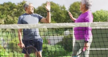 Tenis antrenmanı sırasında çiftler arası mutlu çiftin el çırpışlarının videosu. aktif emeklilik yaşam tarzı, kıdemli ilişki ve tenis eğitim konsepti.