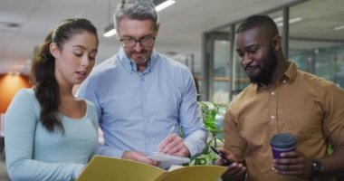 Çeşitli erkek ve kadın iş arkadaşları konuşuyor ve ellerinde belgeler var. Modern bir ofiste çalışmak..