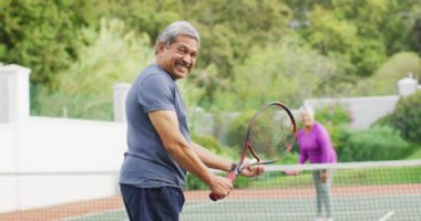 Elinde raket tutan ve tenis kortunda maç başlatan mutlu son sınıf öğrencisinin videosu. aktif emeklilik yaşam tarzı, kıdemli ilişki ve tenis eğitim konsepti.