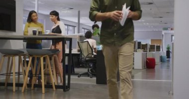 Çeşitli erkek ve kadın iş arkadaşları konuşuyor ve ofiste yürüyorlar. Modern bir ofiste çalışmak..