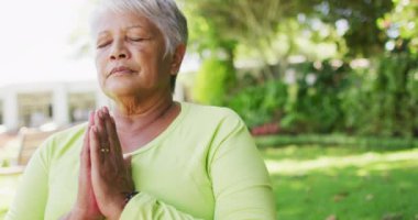 Bahçede yoga yapan rahat, çift ırklı son sınıf kadınının videosu. aktif emeklilik yaşam tarzı ve egzersiz konsepti.