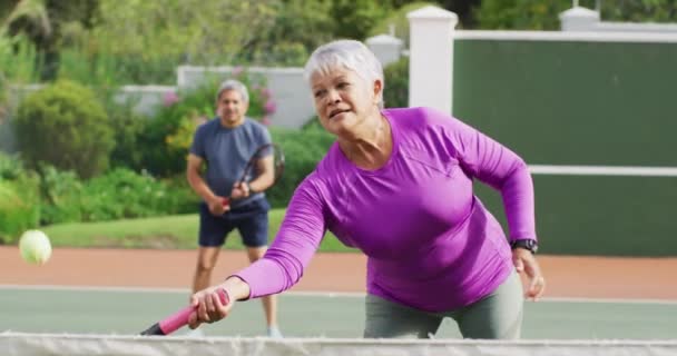 Video Feliz Mujer Mayor Birracial Practicando Tenis Pista Tenis Estilo — Vídeo de stock