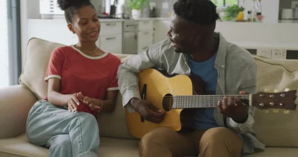 Vídeo Feliz Casal Afro Americano Sentado Sofá Cantando Tocando Guitarra — Vídeo de Stock