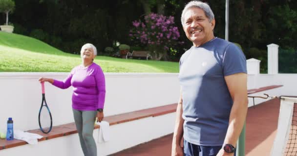 Video Feliz Pareja Ancianos Birraciales Mirando Cámara Cancha Tenis Estilo — Vídeos de Stock