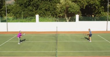 Tenis kortunda oynayan mutlu çift ırklı yaşlı çiftin videosu. aktif emeklilik yaşam tarzı, kıdemli ilişki ve tenis eğitim konsepti.