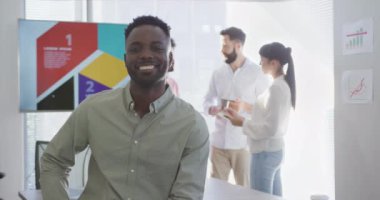 Mutlu Afro-Amerikan iş adamının portresi ofisteki çeşitli meslektaşlar yerine. Modern bir ofiste çalışmak..