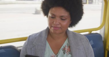 Otobüste akıllı telefon kullanan mutlu ve melez bir kadın. dijital göçebe hareket halinde, beden içeriği.