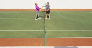 Tenis kortunda maçtan sonra kucaklaşan mutlu yaşlı çiftin videosu. aktif emeklilik yaşam tarzı, kıdemli ilişki ve tenis eğitim konsepti.