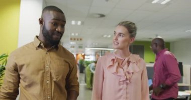 Çeşitli erkek ve kadın iş arkadaşları konuşuyor ve ofiste yürüyorlar. Modern bir ofiste çalışmak..