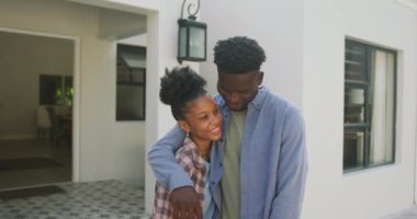 Yeni evin önünde kucaklaşan mutlu Afro-Amerikan çiftin videosu. Aşk, ilişki ve birlikte yeni bir hayata başlamak..
