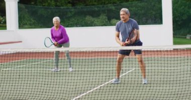Tenis kortunda antrenman yaparken çift ırklı mutlu çiftin videosu. aktif emeklilik yaşam tarzı, kıdemli ilişki ve tenis eğitim konsepti.