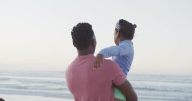 Afrika kökenli Amerikalı baba oğlunu güneşli sahilde taşıyor. sağlıklı ve aktif zaman plaj tatili.
