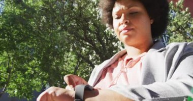 Artı, çift ırklı bir kadın akıllı olanı kontrol ediyor ve şehirde yürüyor. dijital göçebe hareket halinde, beden içeriği.