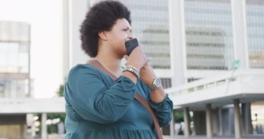 Mutlu ve çift ırklı bir kadın akıllı telefondan konuşuyor ve akıllı saatleri kontrol ediyor. dijital göçebe hareket halinde, beden içeriği.