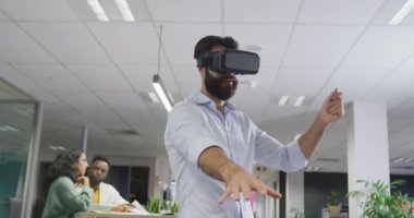 Çift ırklı mutlu iş adamı ofisteki meslektaşlarına karşı kulaklık kullanıyor. Modern bir ofiste çalışmak..