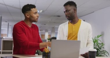 Çeşitli erkek iş arkadaşları konuşuyor ve dizüstü bilgisayar kullanıyor. Modern bir ofiste çalışmak..