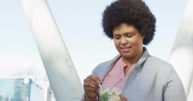 Ayrıca şehirde salata yiyen melez bir kadın. dijital göçebe hareket halinde, beden içeriği.