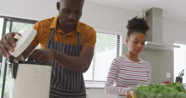 幸せなアフリカ系アメリカ人のカップルがキッチンで一緒に料理をするビデオ 家庭で質の高い時間を過ごすことです — ストック動画