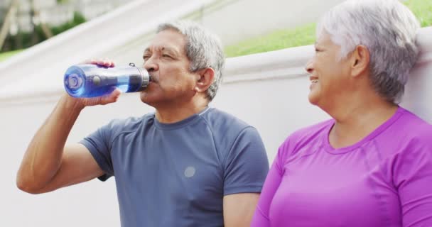 Vídeo Feliz Pareja Mayor Birracial Bebiendo Agua Después Del Partido — Vídeo de stock