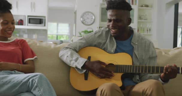 Vídeo Feliz Casal Afro Americano Sentado Sofá Cantando Tocando Guitarra — Vídeo de Stock