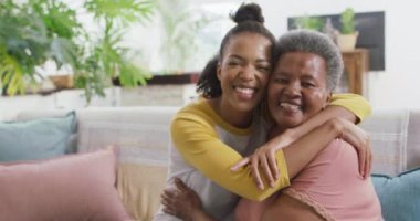 Evde birbirlerine sarılırken gülümseyen Afro-Amerikan anne ve kızının portresi. annelik ve aşk kavramı