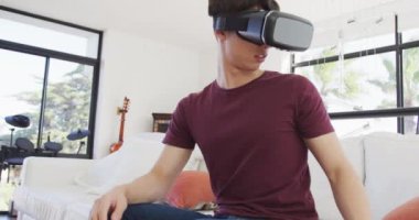 VR kulaklık takan Asyalı çocuk evdeki oturma odasında el kol hareketi yapıyor. Genç yaşam tarzı ve yaşam konsepti