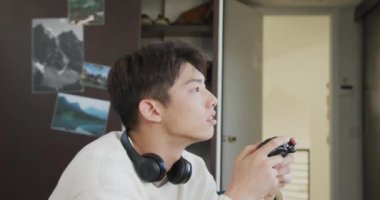 Asyalı çocuk evdeki kanepede oturmuş video oyunu oynuyor. Genç yaşam tarzı ve yaşam konsepti