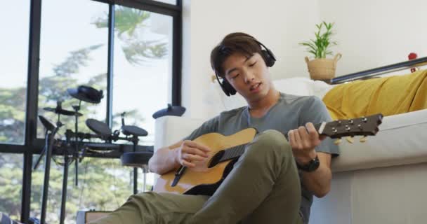 Niño Asiático Con Auriculares Tocando Guitarra Sala Estar Casa Estilo — Vídeos de Stock