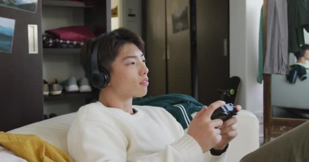 Asian Boy Wearing Headphones Playing Video Games Sitting Couch Home — Stock Video