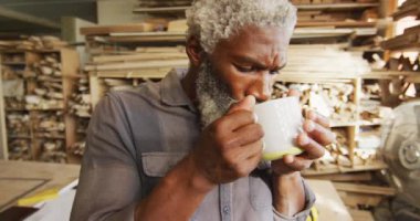 Afro-Amerikan erkek marangoz bir marangozhanede kahve içiyor. Marangozluk, işçilik ve el işi konsepti