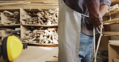 Afro-Amerikan erkek marangozun bir marangoz dükkanında önlük giydiği orta bölüm. Marangozluk, işçilik ve el işi konsepti