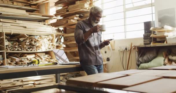 African American Male Carpenter Using Smartphone While Drinking Coffee Carpentry — Stockvideo