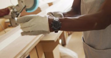 Afro-Amerikan erkek marangozun orta bölümü bir marangozhanede güvenlik eldiveni takıyor. Marangozluk, işçilik ve el işi konsepti