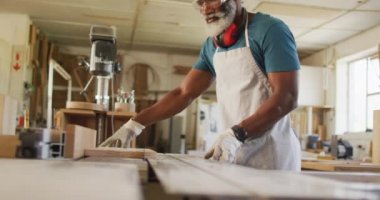 Close up of african american male carpenter hand's using table saw for cutting wood. carpentry, craftsmanship and handwork concept